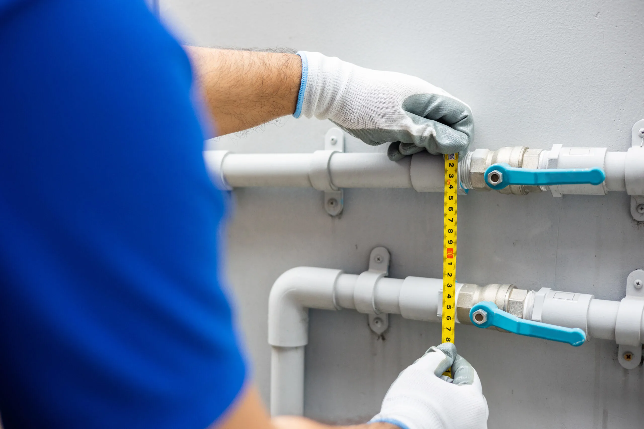 A worker is installing a thermal head on the home heating system distributor.